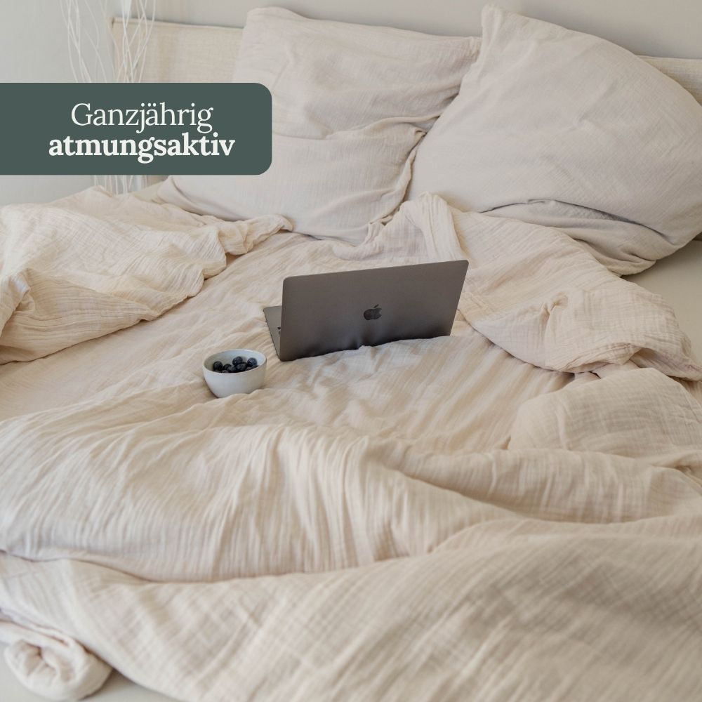 Cremefarbene Musselin-Bettwäsche mit Laptop auf dem Bett – ganzjährig atmungsaktiv