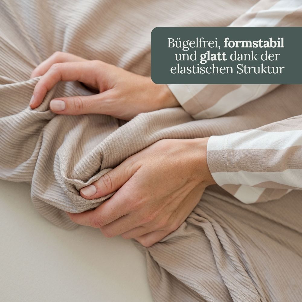 Hände auf taupefarbener Struktur-Bettwäsche – bügelfrei und formstabil