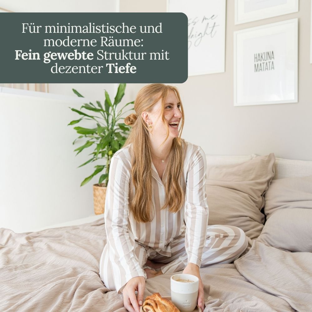 Lachende Frau mit Frühstück im Bett mit taupefarbener Struktur-Bettwäsche