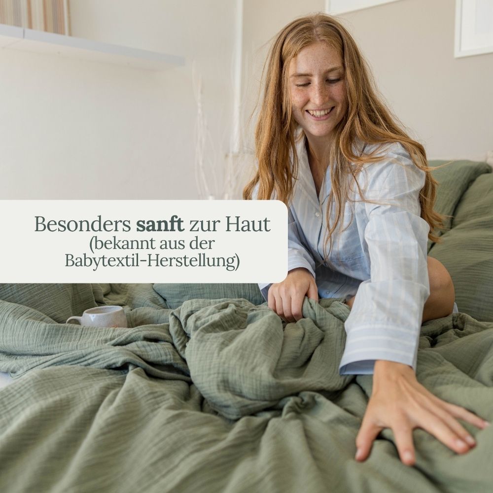 Lächelnde Frau im Bett mit olivgrüner Musselin-Bettwäsche – besonders sanft zur Haut