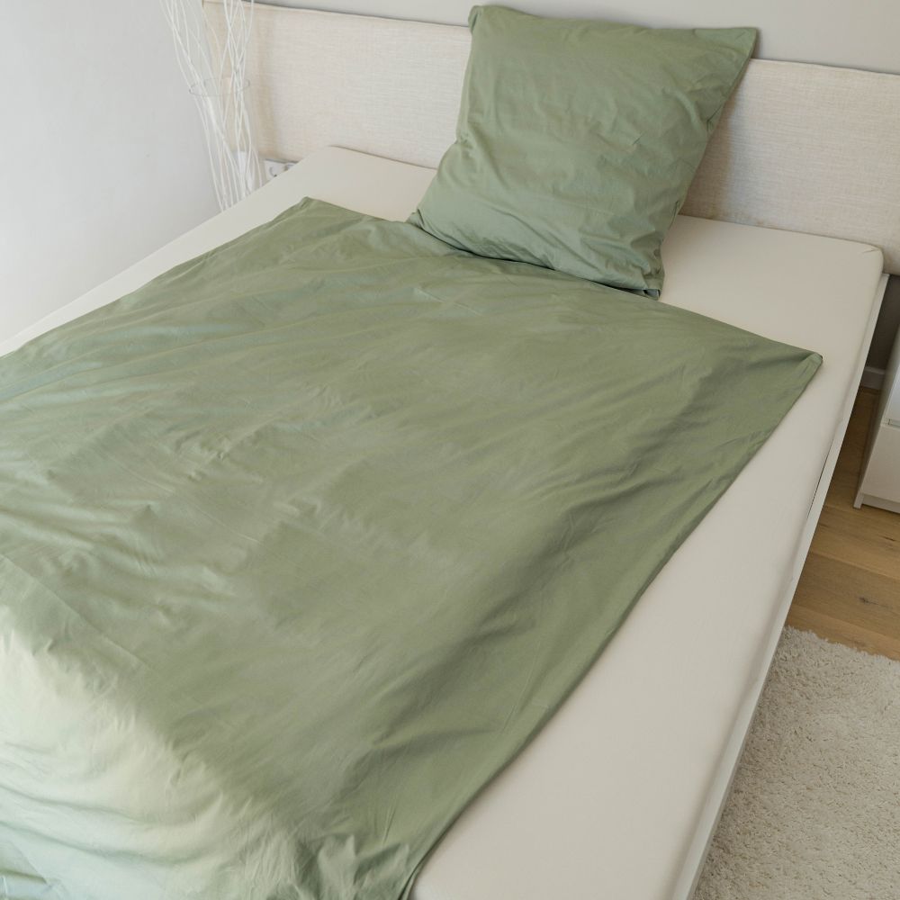 Olivgrüner Perkal-Deckenbezug mit Kopfkissen auf einem hellen Bett