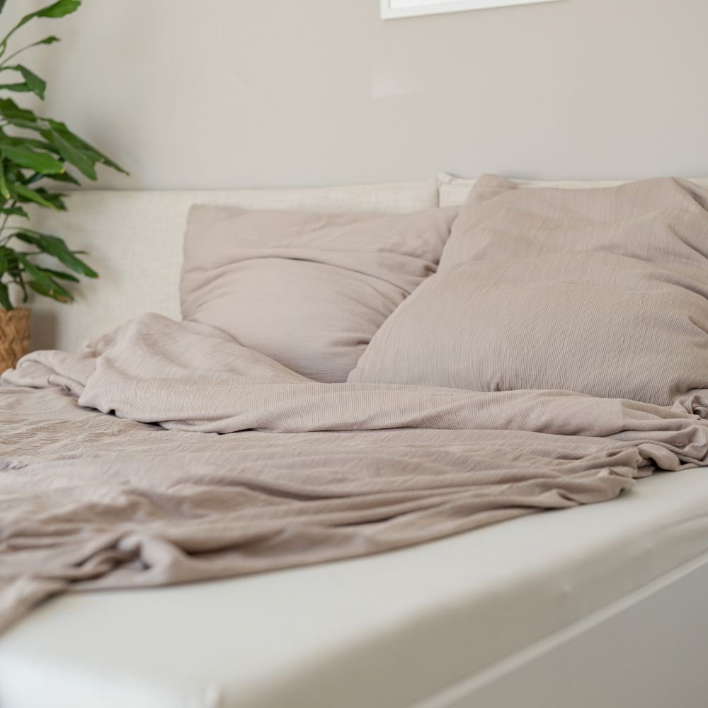 Bett mit taupefarbener Struktur-Bettwäsche aus Bio-Baumwolle und Kopfkissen